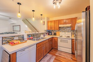 Eine moderne Küche mit Holzschränken, einem Edelstahlkühlschrank und einer gefliesten Spritzschutzwand.