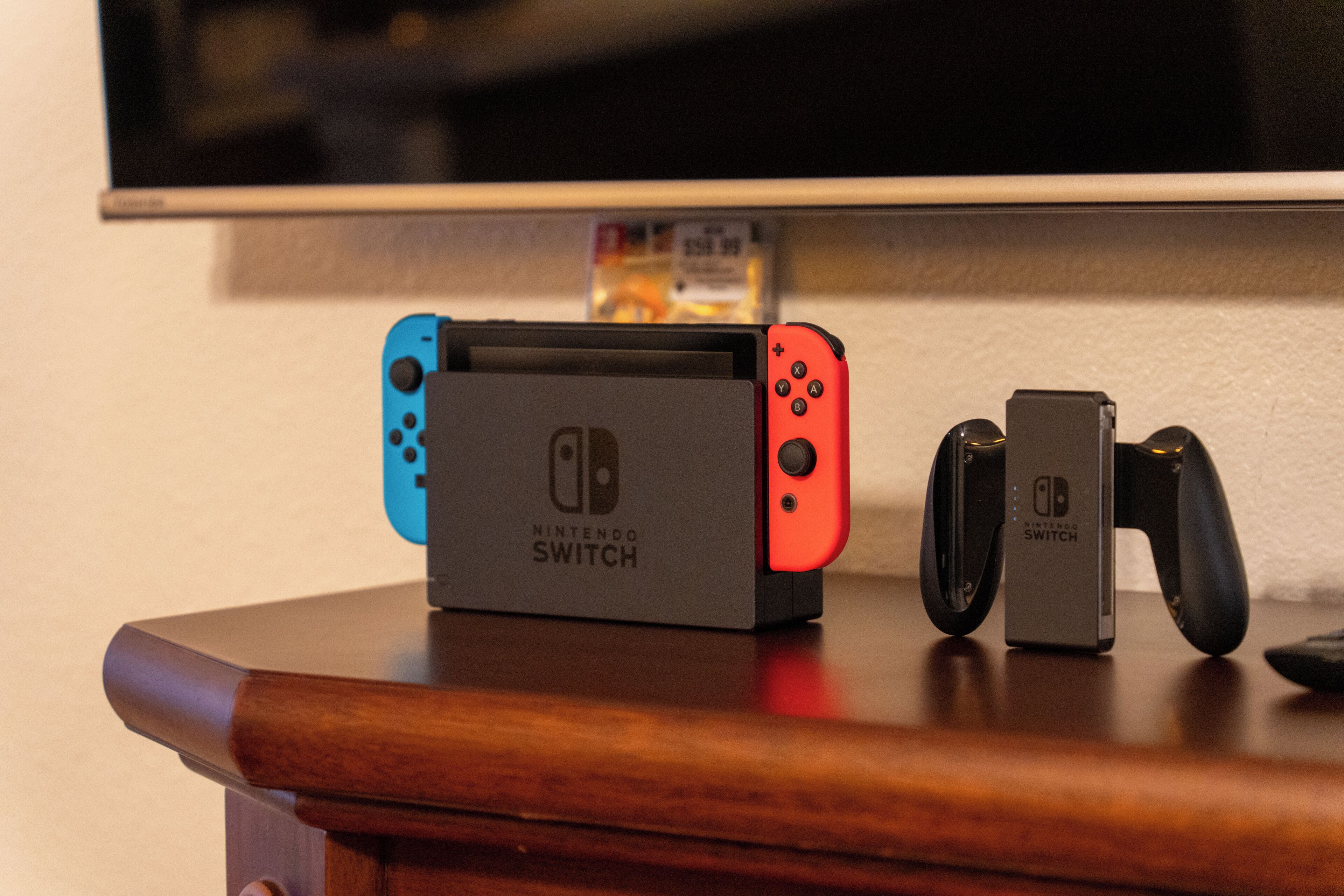 A Nintendo Switch console and controllers on a wooden surface.