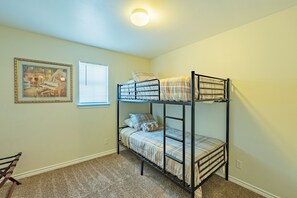 Habitación con literas, una luz en el techo, un cuadro en la pared y una ventana con persianas.