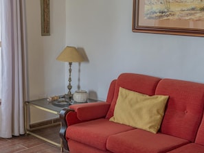 A red sofa with a single cushion, a glass coffee table with a lamp, and a framed painting on the wall. - CHL Basilisa Capote traditional House (El Paso)