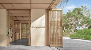 Entrada de un edificio moderno con fachada de madera y un letrero que dice 'ALLA LIVING'.