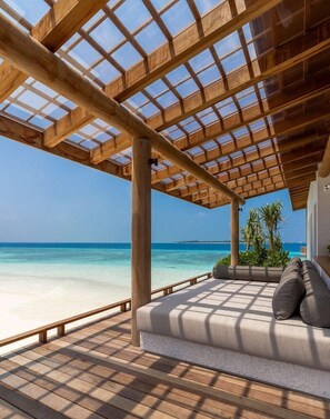A wooden deck with a glass ceiling overlooking a beach.