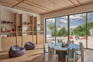 A modern interior with a large window, wooden cabinets, and a round table with chairs. - Alila Kothaifaru Maldives (Kothaifaru)