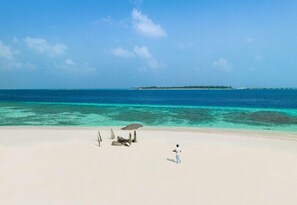 A beach with clear turquoise water, a sandy shore, and a small island in the distance. - Alila Kothaifaru Maldives (Kothaifaru)