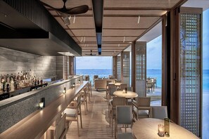 Zona de bar con vistas al mar, mobiliario de madera y un diseño de techo moderno.