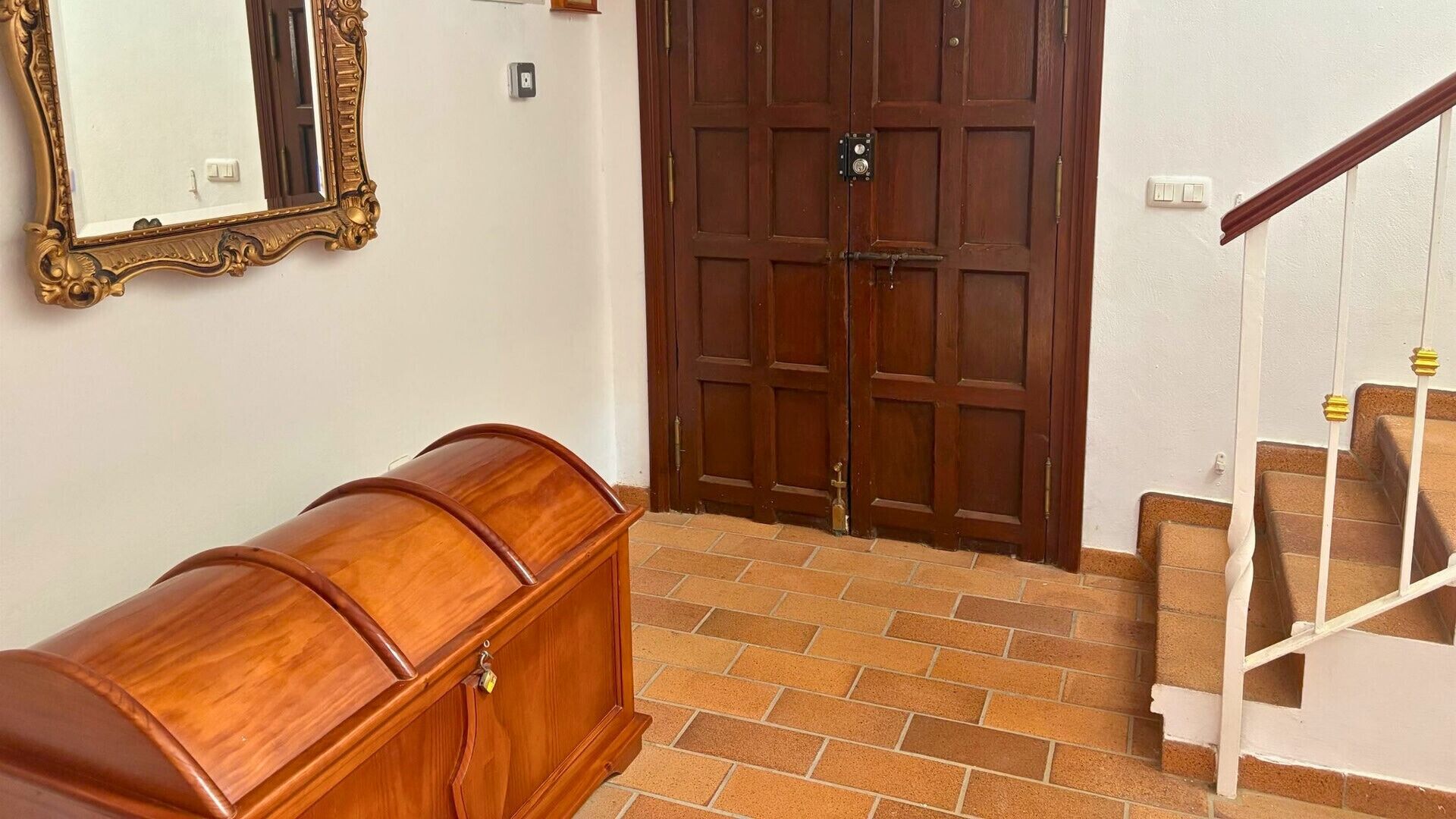 Un banc en bois, une porte à deux battants et un escalier muni d’une main courante.