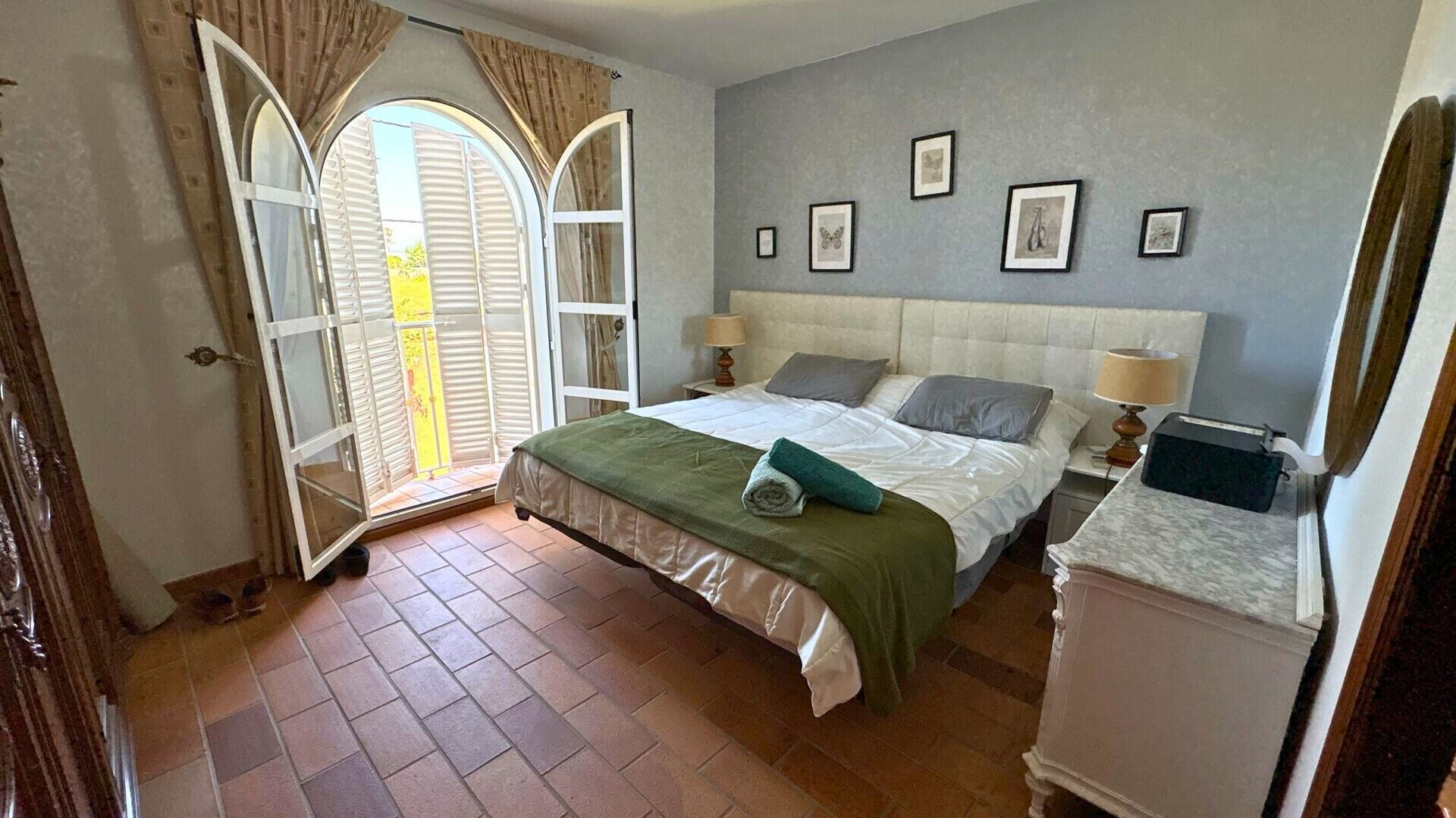 A bedroom with a bed, a nightstand, a dresser, and a window with curtains.