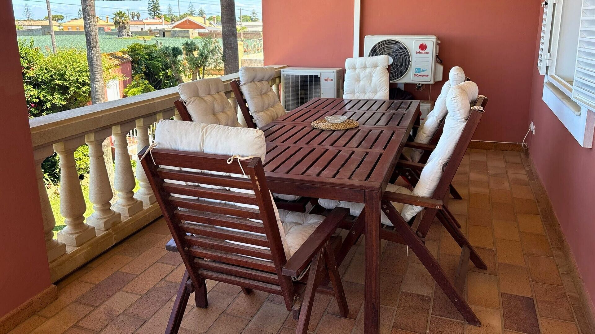 Un balcon avec une table et des chaises en bois, un appareil de climatisation et une vue sur les environs.