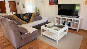 A living room with a sofa, coffee table, TV stand, and decorative items.