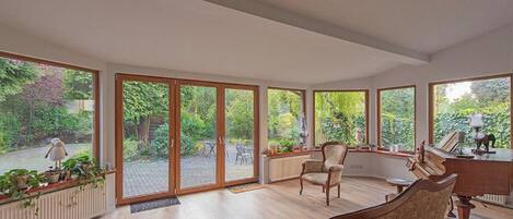 A spacious room with large windows, a piano, and a chair.