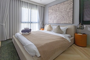 A modern bedroom with a large bed, a decorative wall piece, and a nightstand with a lamp. - The Title Legendary Designer 2BR near Bang Tao Beach (Choeng Thale)