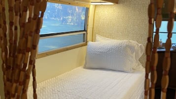 Una cama con colchón acolchado, una ventana con vistas a árboles y armarios de madera.