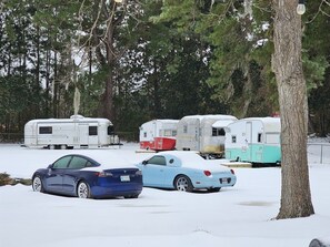 A parking lot with snow-covered ground, several trailers, and two cars. - Vintage Shasta, Glamping for two near Savannah, Hinesville, and Beaches (Midway)
