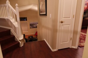 A staircase leading to a landing with a door and a framed picture on the wall. - Updated Modern 3-Bedroom Home with Private Hot Tub (Littleton)