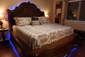 Ein Bett mit einem gemusterten Überwurf, einem Holzkopfstück und zwei Nachttischlampen.