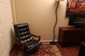 A room with a black leather chair, a wooden cabinet, a television, and a patterned rug. - Updated Modern 3-Bedroom Home with Private Hot Tub (Littleton)