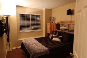 A bedroom with a bed, a wardrobe, a globe on top of the wardrobe, a lamp, and a window with blinds. - Updated Modern 3-Bedroom Home with Private Hot Tub (Littleton)