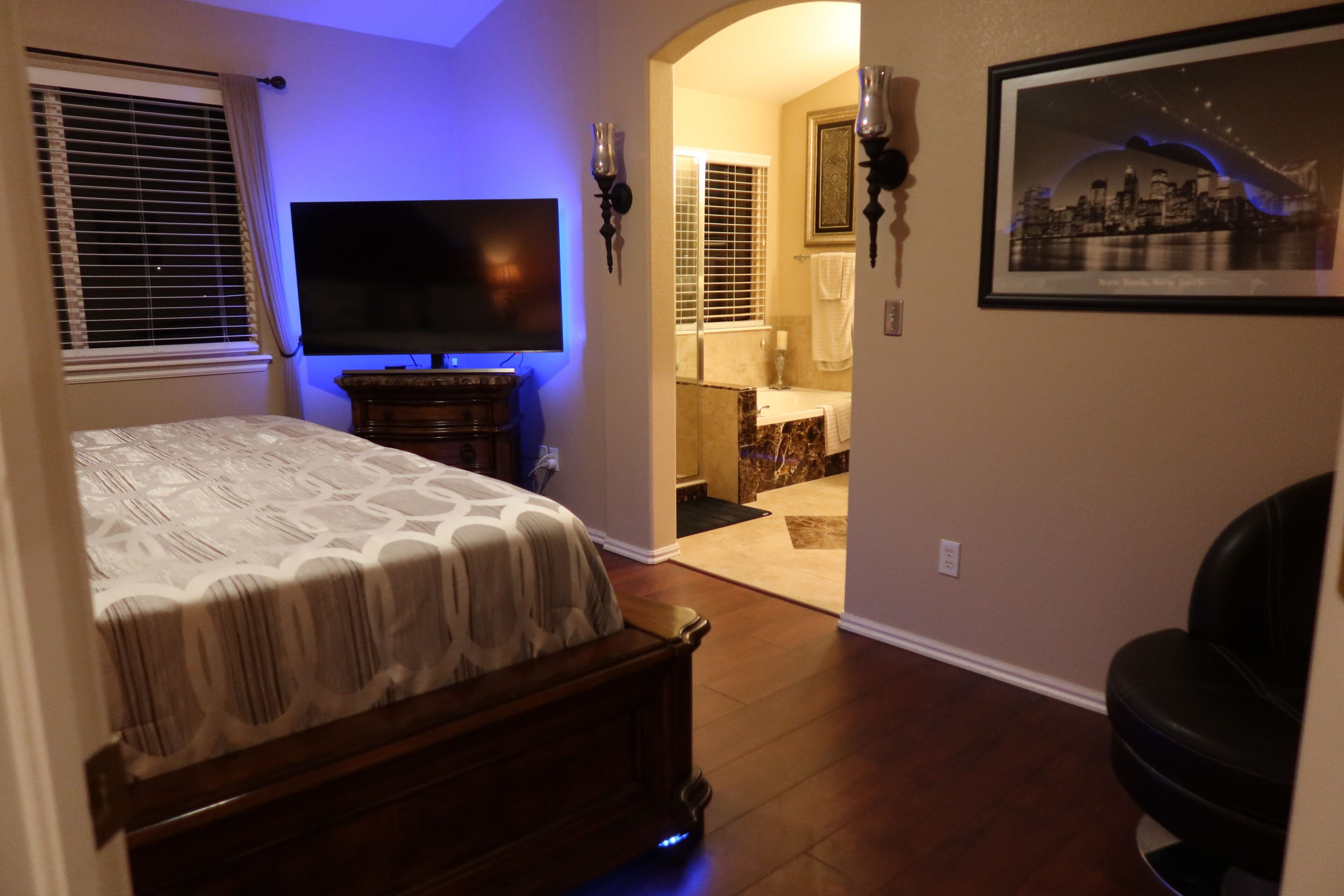 A bedroom with a bed, a television, and a bathroom visible through an open door.