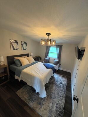 A bedroom with a bed, bedside tables, a rug, and a ceiling light fixture. - Private cabin retreat with everything you need! (Independence)