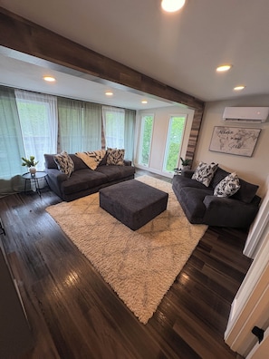 A modern living room with a sectional sofa, ottoman, and a large rug. - Private cabin retreat with everything you need! (Independence)