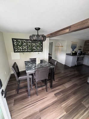 A dining area with a marble table and leather chairs, a kitchen with modern appliances, and a wooden ceiling beam. - Private cabin retreat with everything you need! (Independence)