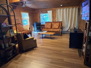 A cozy living room with a fireplace, wooden furniture, and a television. - Riverfront log cabin with 200 feet private water front and beautiful views !  (Pulaski)