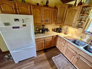 A kitchen with wooden cabinets, a white refrigerator, a coffee maker, and a sink. - Riverfront log cabin with 200 feet private water front and beautiful views !  (Pulaski)