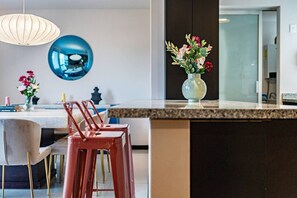 Eine moderne Küche mit Marmorarbeitsplatte, einer Blumenvase und einem blauen, kugelförmigen Objekt an der Wand.