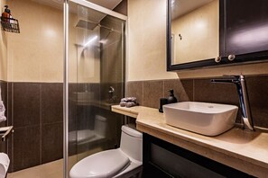 A modern bathroom with a glass-enclosed shower, a white toilet, and a large vessel sink with a faucet. - Designer Apt in Roma Norte, Parking & Workspace (Mexico City)