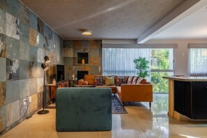 A modern living room with a stone wall, a sofa, a coffee table, and a large window. - Designer Apt in Roma Norte, Parking & Workspace (Mexico City)