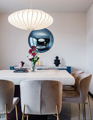 A dining area with a large table, chairs, a hanging light fixture, a decorative mirror, and a vase with flowers. - Designer Apt in Roma Norte, Parking & Workspace (Mexico City)