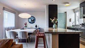 A modern kitchen with a central island, a dining area with a round table, and a living space with a sofa. - Designer Apt in Roma Norte, Parking & Workspace (Mexico City)