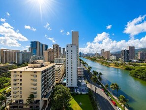 A high-rise building with a river in the background, surrounded by other buildings and greenery. - Luxe Island Retreat – Modern Coastal Design (Honolulu)