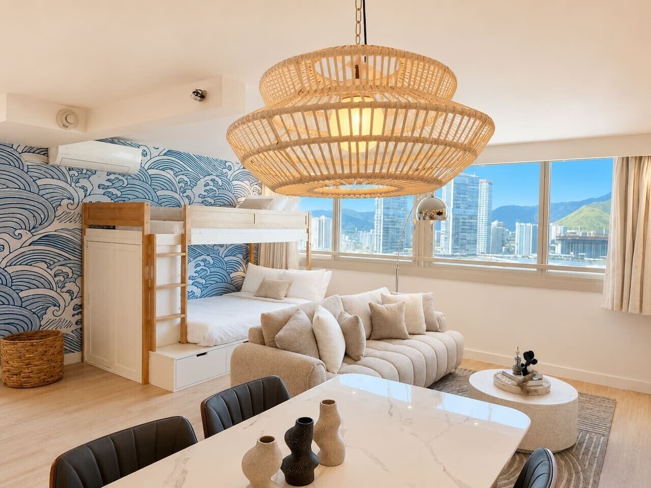 Une chambre moderne équipée d’un lit superposé, d’un canapé, d’une table à manger et d’une grande fenêtre donnant sur la ville.