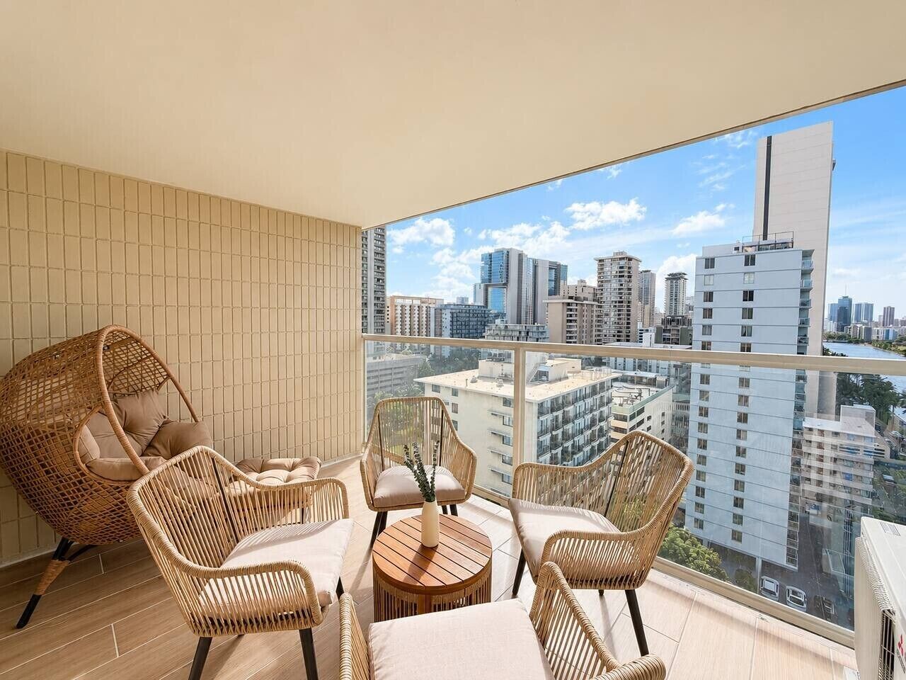 Ein Balkon mit Korbmöbeln und Blick auf die Stadt.