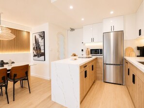 Eine moderne Küche mit einer Kochinsel, Edelstahlgeräten und einem Essbereich mit einem Holztisch und Stühlen.