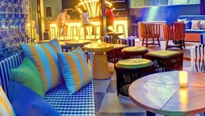 Un área de lounge moderna con arreglos de asientos, una zona de bar y un ventanal con vistas.