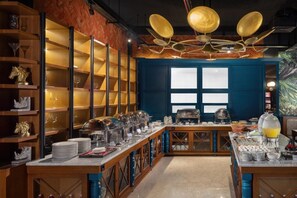 A buffet setup with multiple serving stations, glassware, and a decorative ceiling light fixture. - Luminor Hotel Palembang (Palembang)