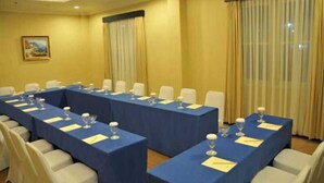 Un salón de conferencias con varias mesas, sillas y un cuadro en la pared.