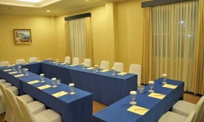 Ein Konferenzraum mit mehreren Tischen, Stühlen und einem Gemälde an der Wand.