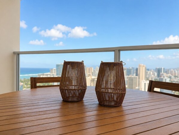 Una mesa de madera con dos jarrones de mimbre, con vistas a un paisaje urbano que incluye edificios y una masa de agua.
