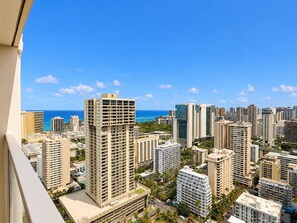 A high-rise urban area with multiple buildings, a clear blue sky, and a distant view of the ocean. - 41F Modern Waikiki Retreat – Luxe Coastal Style (Honolulu)