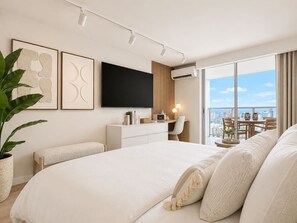A modern hotel room with a large bed, a desk, a chair, and a balcony with a city view. - 41F Modern Waikiki Retreat – Luxe Coastal Style (Honolulu)