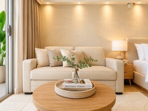 A living room with a beige sofa, a coffee table with a book, and a lamp. - 41F Modern Waikiki Retreat – Luxe Coastal Style (Honolulu)