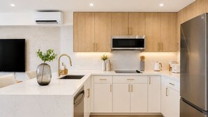 Een moderne keuken met witte kasten, roestvrijstalen apparatuur en een marmeren werkblad.