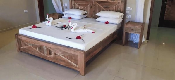Una cama con estructura de madera, ropa de cama blanca y figuras decorativas de cisnes.