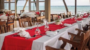 Um restaurante com mesas preparadas para refeições, com vista para o mar.