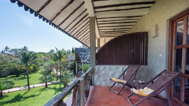 Uma varanda com vista para um jardim e um edifício.