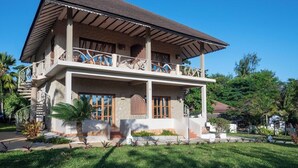Um edifício de dois andares com varanda, alpendre coberto e um gramado bem cuidado.
