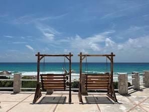 Ein hölzernes Schaukelgerüst mit Blick auf einen Strand und eine klare Sicht auf den Ozean.